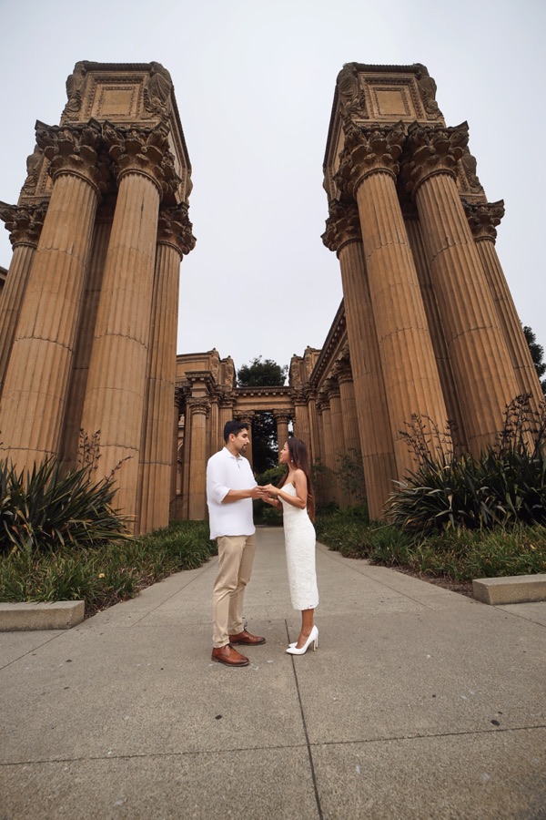 Trinique and Juan Pablo holding hands between towering stone columns